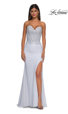A woman stands against a plain background wearing the Strapless Sweetheart Prom Gown: La Femme 32961, featuring a beaded corset bodice, high slit, and silver heels.