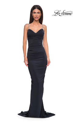 A woman wearing the fitted, floor-length black Backless Ruched Long Prom Dress: La Femme 32970 with thin jeweled straps stands against a white background. The La Femme logo is in the top right corner.