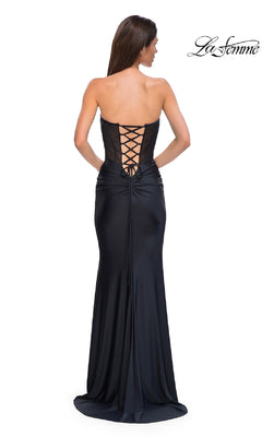 A woman stands with her back to the camera wearing the Strapless Long Corset Prom Dress: La Femme 32971. The fitted gown features lace-up back detailing and an elegant silhouette through the waist and hips.