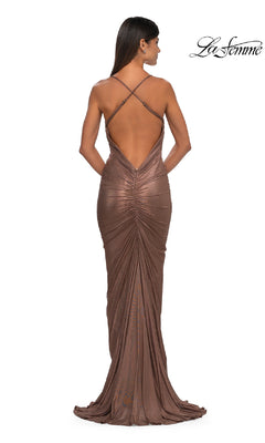 A woman wears the La Femme 32973 Backless Metallic Jersey Prom Dress in brown, featuring a floor-length design, low back, and crisscross straps, standing with her back to the camera. La Femme logo appears in the top right corner.