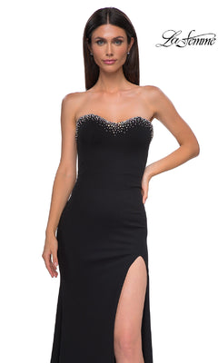 A woman wears the Strapless Long Black Prom Dress: La Femme 32975—an elegant gown featuring a thigh-high slit and beaded neckline detailing.