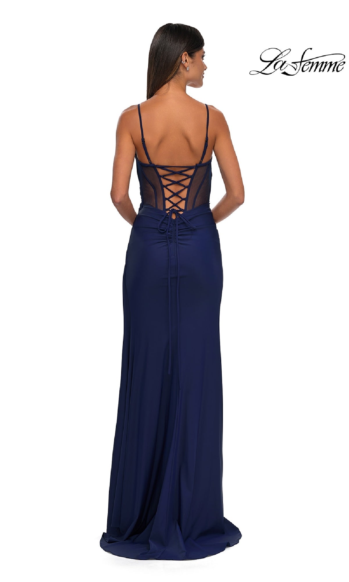 Woman in a navy blue Side-Sash Lace-Up Long Prom Dress (La Femme 32977) with spaghetti straps, lace-up back, and sheer paneling, standing with her back to the camera.