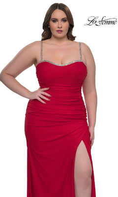 Plus-size model wearing a fitted red La Femme 32992 prom dress with jeweled straps and a thigh-high slit, standing against a white background with the "La Femme" logo.