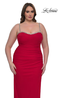 A woman wears the Plus-Size Long Prom Dress: La Femme 32992, a sleeveless fitted red gown with rhinestone straps and ruched details, standing against a white background. The "La Femme" logo appears in the corner.