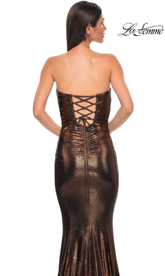A woman is seen from behind wearing the La Femme 32995 Strapless Long Metallic Prom Dress in bronze, featuring a lace-up back, against a white background.