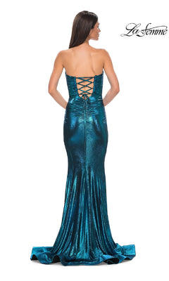 A woman models the La Femme 32995 Strapless Long Metallic Prom Dress in teal, featuring a lace-up back and floor-length skirt. The La Femme logo is visible in the top right corner as she faces away from the camera.