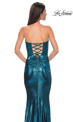 A woman wearing the Strapless Long Metallic Prom Dress: La Femme 32995 in shiny teal, featuring a lace-up back, stands with her back to the camera. The "La Femme" logo appears in the top right corner.