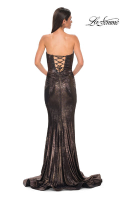 A woman models the La Femme 32995, a strapless long metallic brown prom dress with a lace-up back and slight train, standing against a white background. The "La Femme" logo appears in the top right corner.