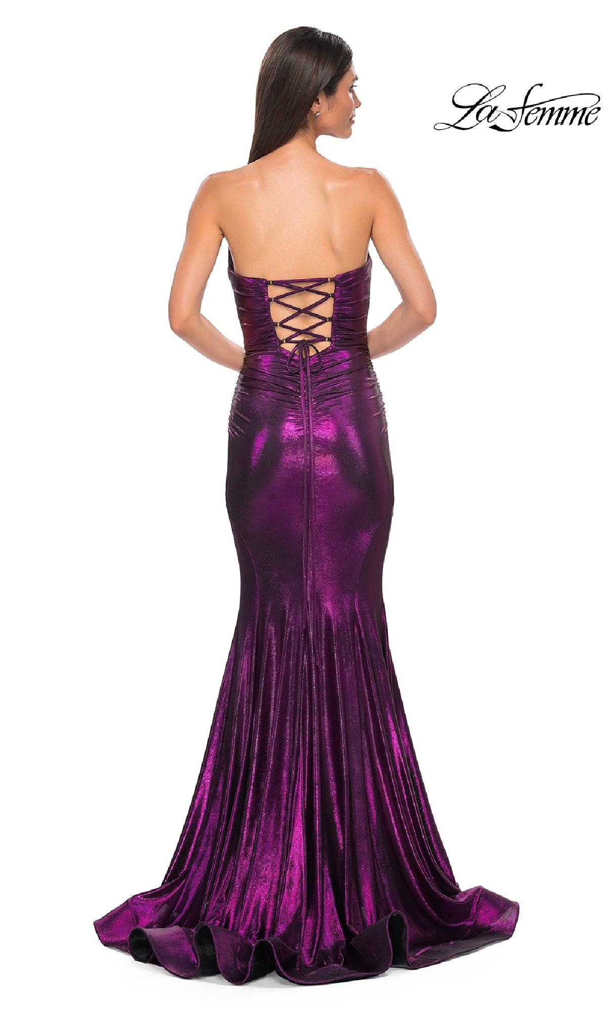 A woman stands facing away from the camera in a strapless long metallic purple La Femme 32995 prom dress with a lace-up back.