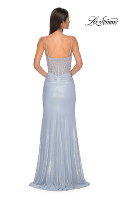 A woman in the Sheer-Corset Long Prom Dress: La Femme 33003 faces away, showing its sheer beaded back panel. This floor-length, sleeveless gown features thin straps, a slight train, and elegant, delicate details.