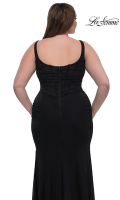 A woman models the Plus-Size Simple Long Prom Dress: La Femme 33005, a fitted sleeveless black evening gown with a sheer panel and zippered back, standing against a white background. The La Femme logo appears in the top right corner.