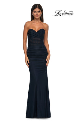 A woman wears the Metallic Strapless Long Prom Dress (La Femme 33007) in navy blue with ruched detailing, standing against a plain white background. The La Femme logo appears in the top right corner.