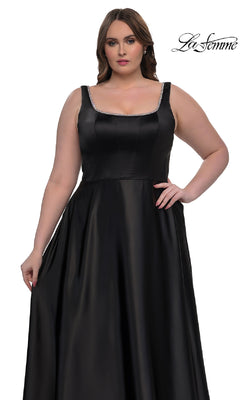 A woman models the Plus-Size Classic Long Prom Gown (La Femme 33026), a sleeveless black satin dress with a fitted bodice and flared skirt, against a white background. The "La Femme" brand name is displayed in the top right corner.