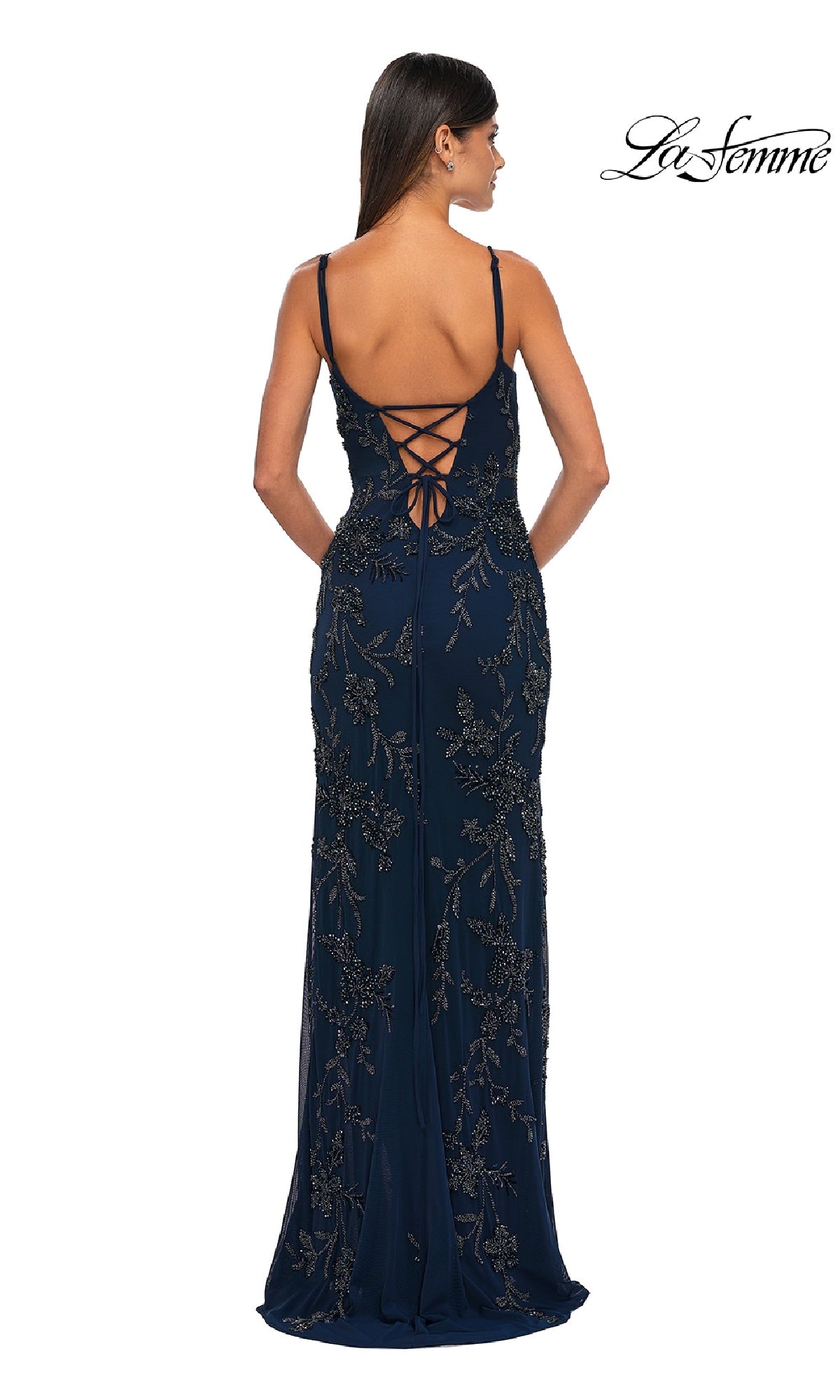 A woman wears the La Femme 33054 Lace-Up Long Beaded Prom Dress in dark blue, featuring floral embellishments and a lace-up back, as she faces away from the camera. The “La Femme” logo is visible in the top right corner.