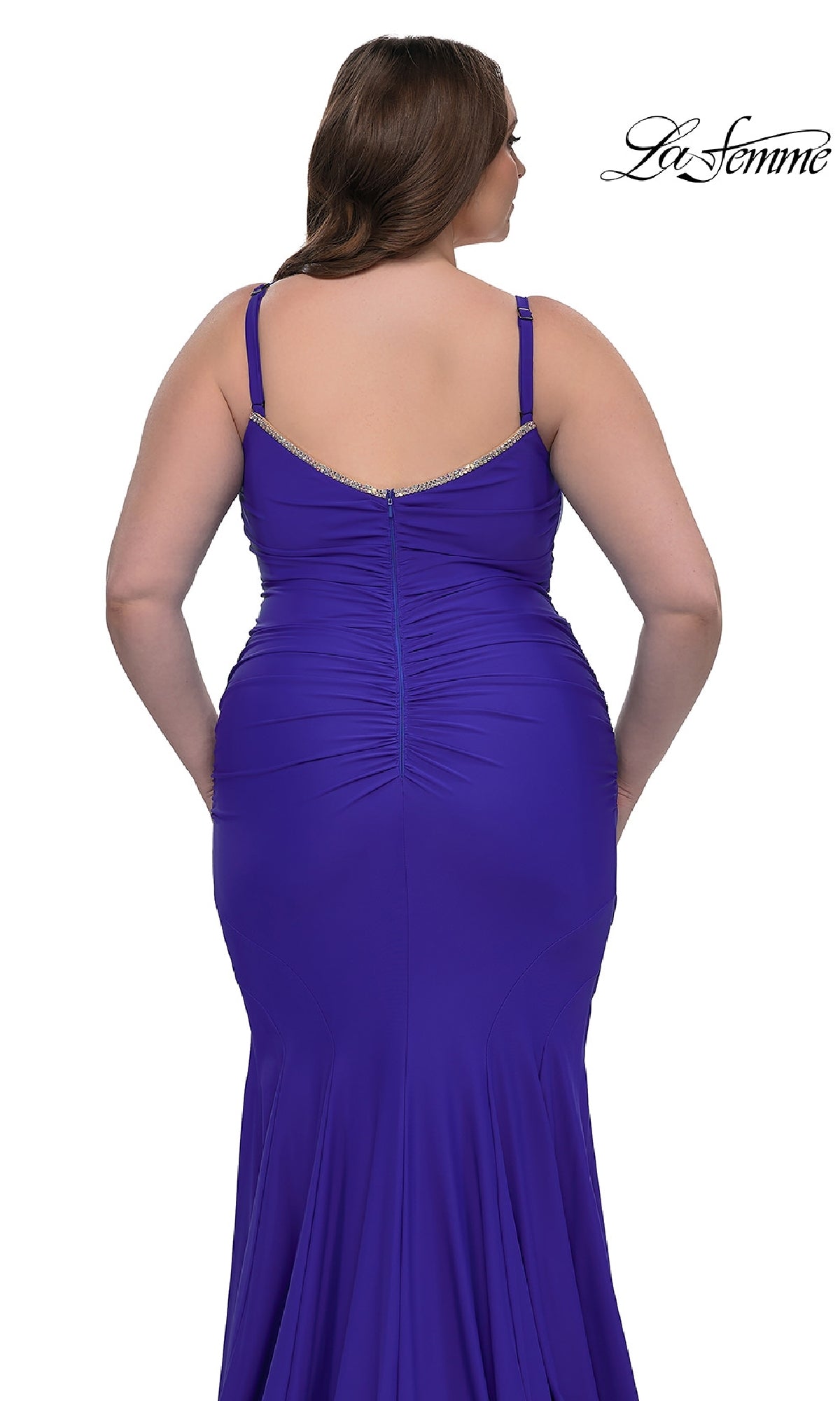 A woman is shown from behind wearing the La Femme 33057 plus-size floor-length prom dress, a fitted royal blue gown with spaghetti straps and a gathered seam down the back.