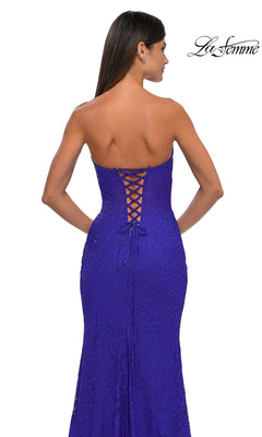 A woman is seen from behind wearing the La Femme 33069 Strapless Long Lace Prom Dress in royal blue, featuring a fitted silhouette, lace-up back detail, and subtle sparkly embellishments.