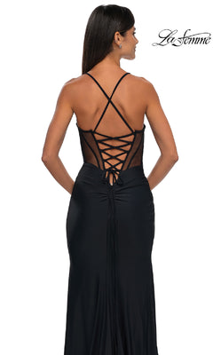 A woman stands with her back to the camera in the Strappy-Back Long Black Prom Dress: La Femme 33115, featuring crisscross and lace-up back details. The "La Femme" logo is displayed in the top right corner.