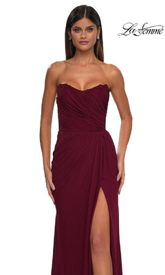 A woman in the Classic Strapless Long Prom Dress: La Femme 33116, burgundy with a sweetheart neckline and high leg slit, poses against a white background. The "La Femme" logo appears in the top right corner.