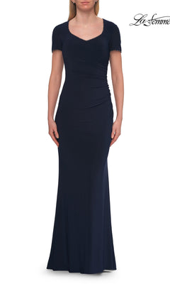 A woman wearing the La Femme 33146 Short Sleeve Long Jersey Formal Dress in navy stands with her arms at her sides against a white background.