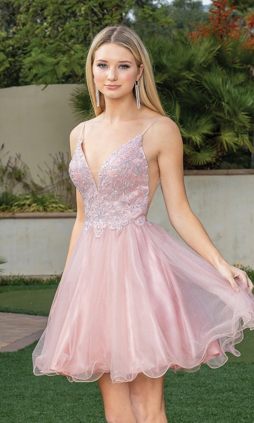 A woman stands outdoors, greenery behind her, wearing a light pink, sleeveless Short Babydoll Homecoming Dress with beading and tulle.