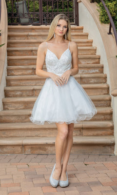A young woman in the Lace-Up-Back Short Babydoll Homecoming Dress 3315 with a beaded corset bodice and heels poses on an outdoor staircase, hands clasped in front of her.