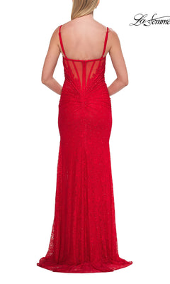 A woman wearing the La Femme 33305 long prom dress—a fitted, floor-length red lace gown with thin straps, a corset bodice, and an open back—stands facing away from the camera.