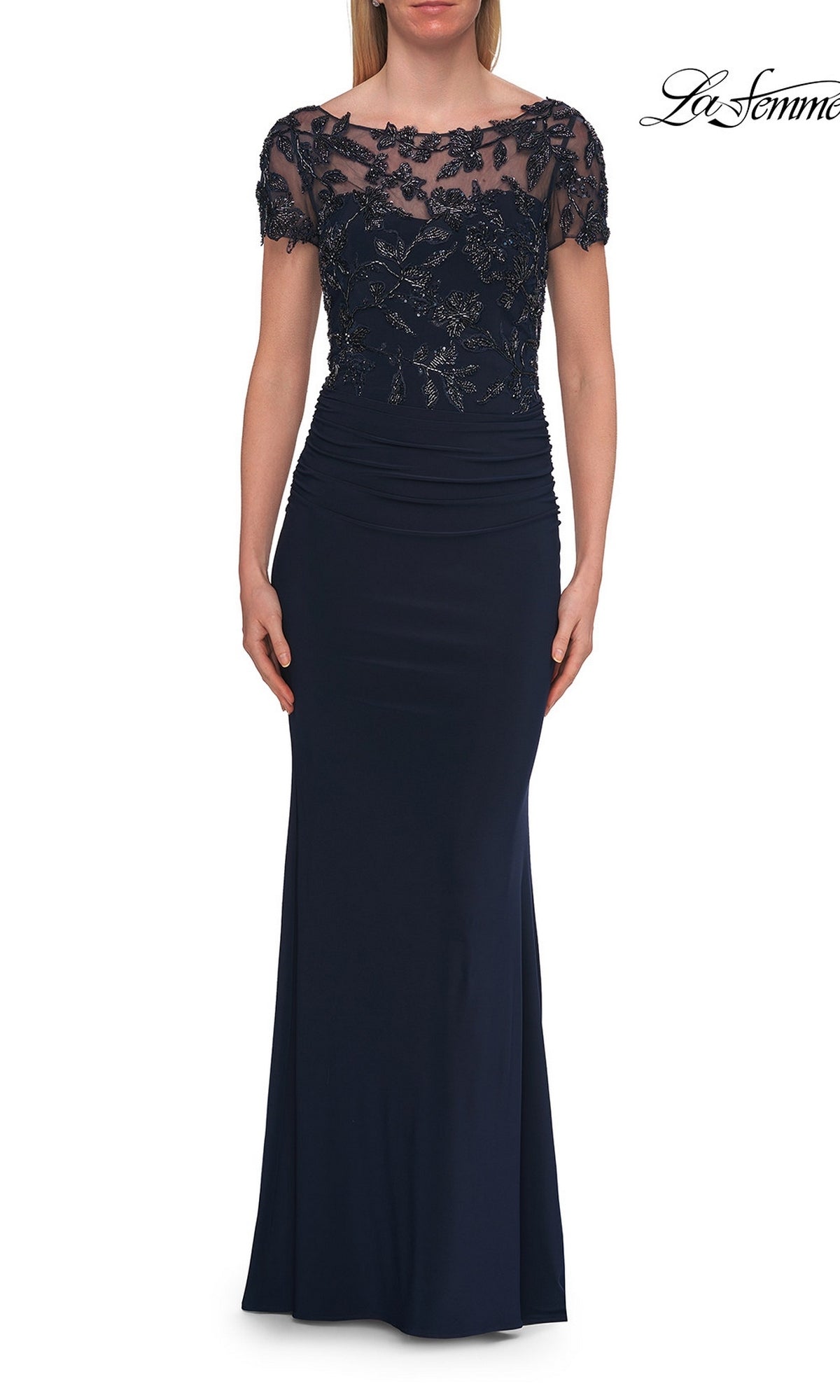 Dressed in the La Femme 33332 Short-Sleeve Beaded Lace Formal Gown in navy, this woman exudes elegance with its floor-length silhouette, embellished lace bodice, short sleeves, and ruched waist detailing—making it a stunning choice for the mother of the bride.