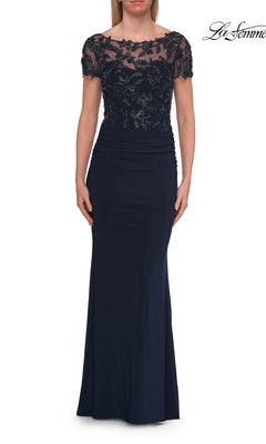 Dressed in the La Femme 33332 Short-Sleeve Beaded Lace Formal Gown in navy, this woman exudes elegance with its floor-length silhouette, embellished lace bodice, short sleeves, and ruched waist detailing—making it a stunning choice for the mother of the bride.