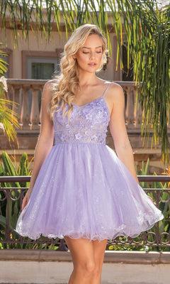 A woman stands outdoors in the Glitter-Tulle Short A-Line Homecoming Dress 3336, featuring light purple tulle, a sleeveless lace bodice with an embellished v-neck, and a short skirt. Lush greenery and a building are visible behind her.