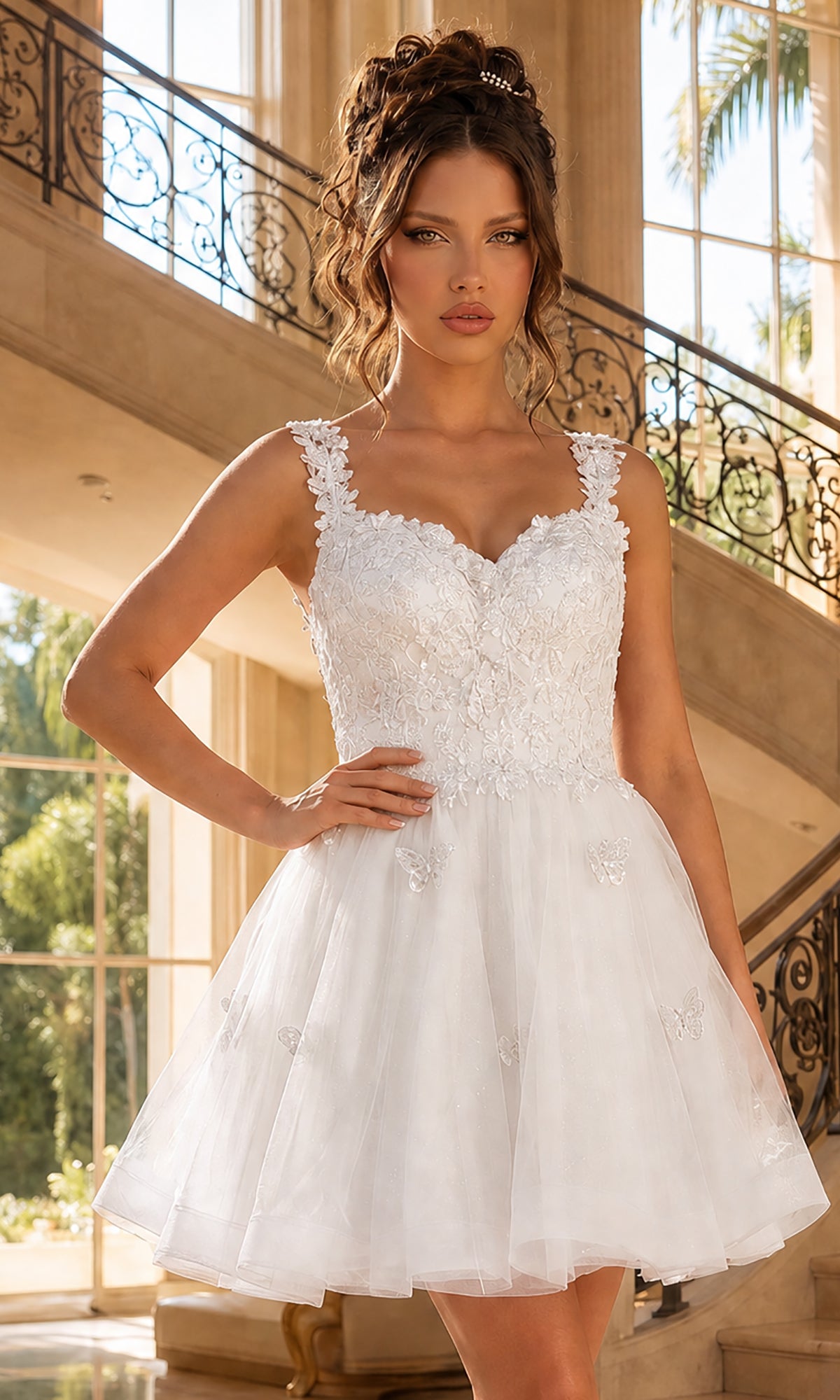 A woman in the Off White Embroidered-Lace Short Babydoll Hoco Dress 3338, featuring a floral appliqué bodice, stands indoors by a staircase and large windows.