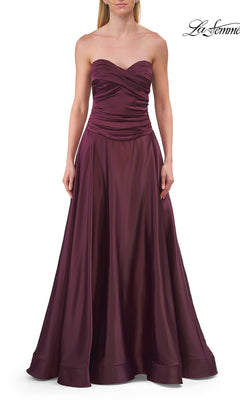 A woman wears the La Femme 33417 Strapless Sweetheart Prom Gown, a floor-length burgundy dress with a ruched bodice and flowing skirt.
