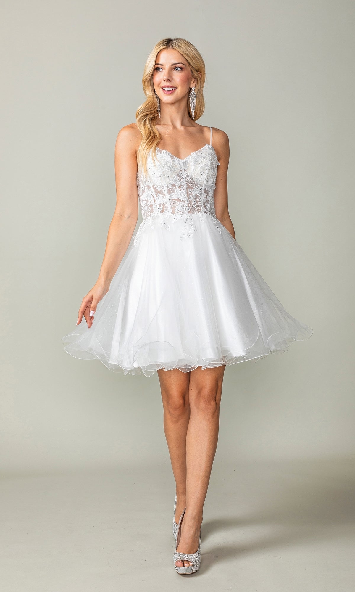 Woman wearing the Lace-Up Short Butterfly Homecoming Dress 3341, featuring a lace bodice and tulle skirt, paired with high heels, standing against a plain light background.