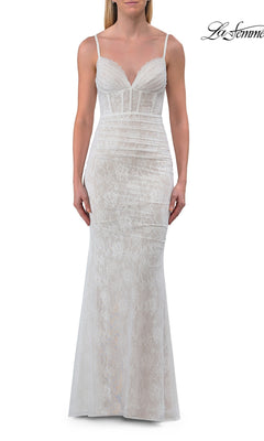 A woman wearing the La Femme 33443, a simple long white lace prom dress featuring a fitted silhouette, thin straps, and a V-neckline, stands against a plain white background.