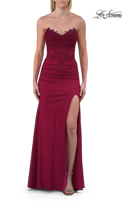 A woman wearing the La Femme 33465 Simple Strapless Long Prom Dress in raspberry, featuring a sweetheart neckline, delicate lace bodice detail, and a thigh-high slit, stands against a plain white background.