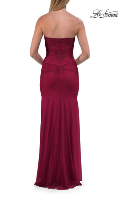A woman is shown from the back wearing the La Femme 33465, a simple strapless long prom dress in maroon with elegant ruching and subtle embellishments.