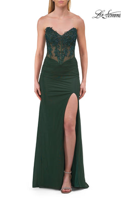 A woman models the Strapless Sheer-Corset Prom Gown, La Femme 33472, in dark emerald—a long dress featuring a strapless silhouette, embellished sheer lace corset bodice, ruched waist, sheer details, and a thigh-high slit—against a white background.