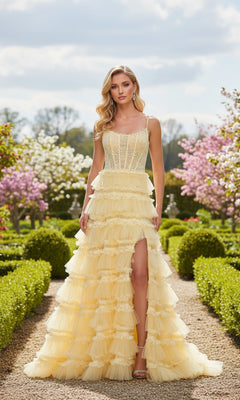 A woman stands in a garden wearing the La Femme 33493 long prom dress in pale yellow, featuring spaghetti straps and a tiered ruffle skirt with a high slit. Manicured hedges and blooming trees are in the background.