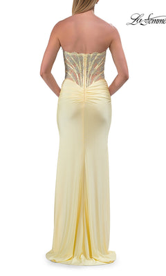 A woman wearing the Strapless Long Mermaid Prom Dress (La Femme 33509) in light yellow, featuring a fitted beaded-lace corset bodice and a long, flowing skirt, shown from the back.
