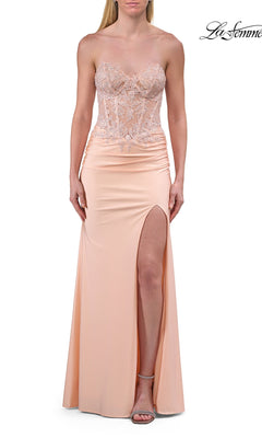A woman stands against a white background wearing the La Femme 33526 Sheer-Corset Strapless Prom Gown in peach, which features a beaded lace corset bodice, fitted waist, and a high leg slit.