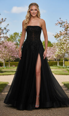 A woman stands on a garden path in the Long Prom Dress: La Femme 33528, a black strapless ball gown featuring a fitted sheer corset bodice, subtle floral embroidery, and a high leg slit.
