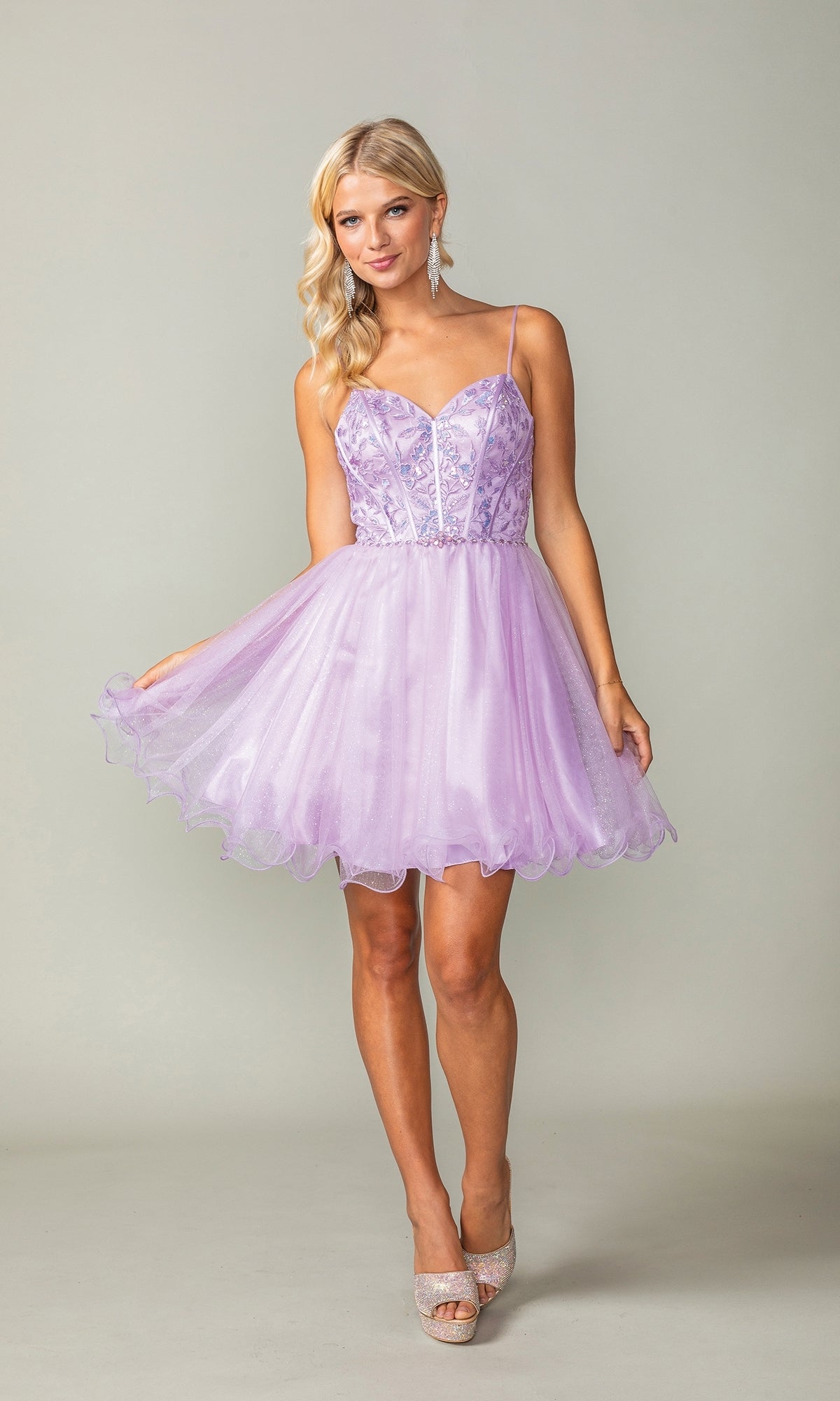 A woman wearing the Lace-Up Short Babydoll Homecoming Dress 3352, featuring a light purple tulle skirt and spaghetti straps, stands against a plain background.