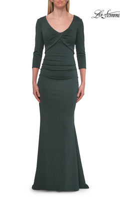 A woman wearing a three-quarter-sleeve, floor-length La Femme 33540 formal gown in dark emerald, featuring a twisted bodice detail and subtle ruching at the waist, stands against a white background—an elegant choice perfect for the mother of the bride.