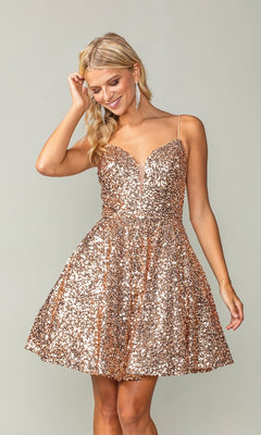 A woman smiles and touches her hair while wearing the Short Sequin A-Line Homecoming Dress 3356, a sleeveless gold dress with a V-neck, thin straps, and shimmering sequins, standing against a plain background.