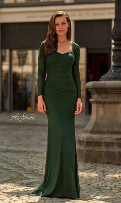 A woman in a La Femme 33575 long formal dress in dark emerald stands on a cobblestone street before a building and stone structure.