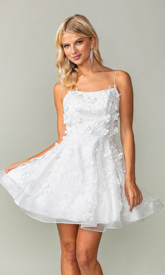 A woman models the Embellished Short Babydoll Homecoming Dress 3357, featuring 3-D floral details, as she stands against a plain background holding the sides of her skirt.