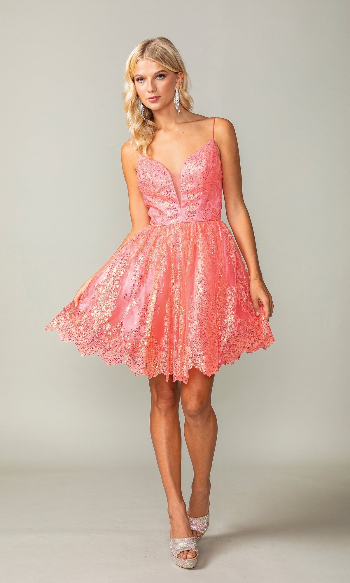 Woman wearing the Scallop Hem Short Glitter Homecoming Dress 3358, a sleeveless pink party dress with spaghetti straps, flared skirt, and scalloped hem, standing against a plain light background.