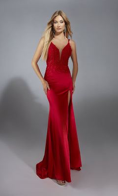 A woman models the Aerie Couture 335, a floor-length red satin prom dress with a leg slit, lace corset bodice, and spaghetti straps, standing against a plain gray backdrop.