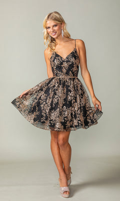 Model wearing the Short A-Line Glitter-Print Homecoming Dress 3360, featuring a sleeveless black design with gold floral patterns, standing and holding the sides of her skirt against a plain background.