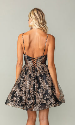 A woman is shown from the back wearing the Short A-Line Glitter-Print Homecoming Dress 3360, featuring black fabric, gold floral embroidery, and lace-up back detailing.