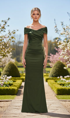 A woman stands on a garden path wearing the Long Prom Dress: La Femme 33620 in olive. Boxwood hedges, blooming flowers, and trees form the background.